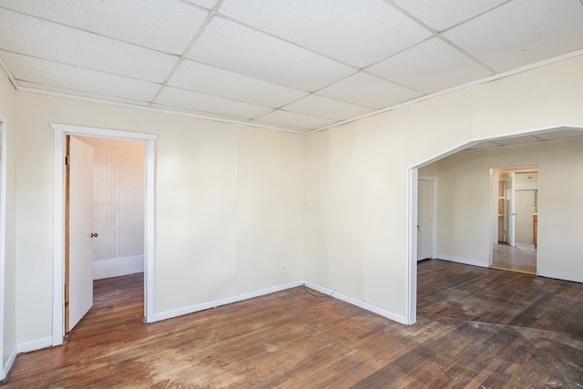 empty room with a drop ceiling and dark wood-type flooring