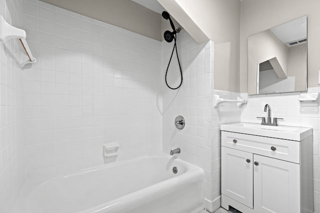 bathroom with vanity, tiled shower / bath, and tile walls