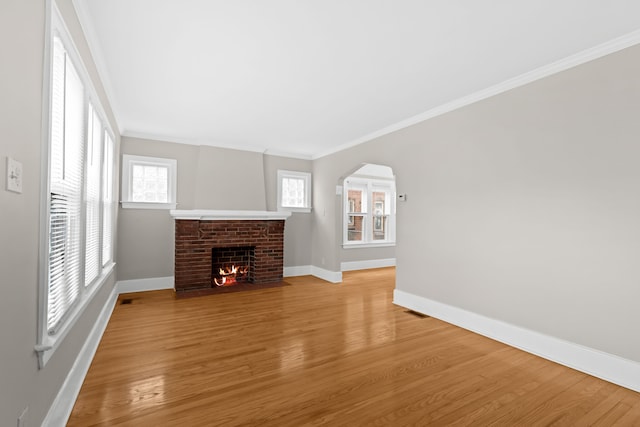 unfurnished living room featuring a fireplace, wood-type flooring, and ornamental molding