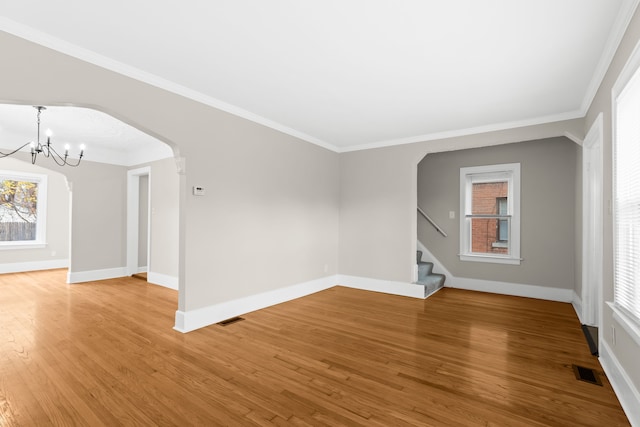 spare room featuring crown molding, hardwood / wood-style floors, and a notable chandelier