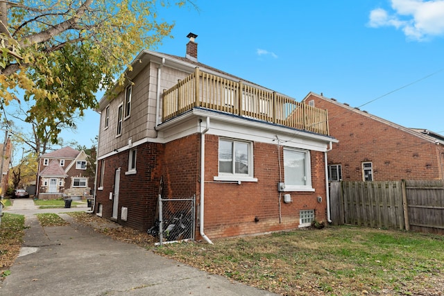 rear view of property with a yard and a balcony