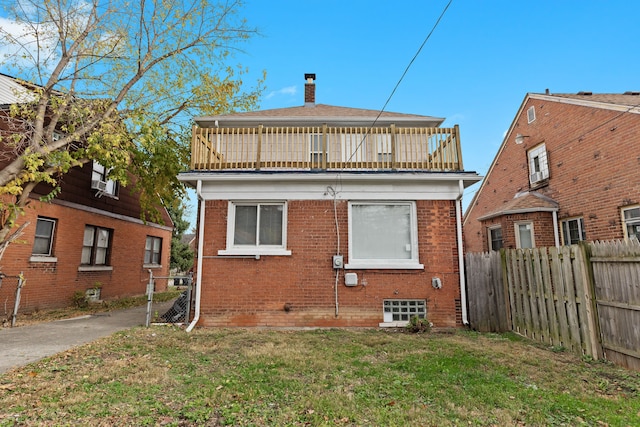 back of property with a yard and a balcony