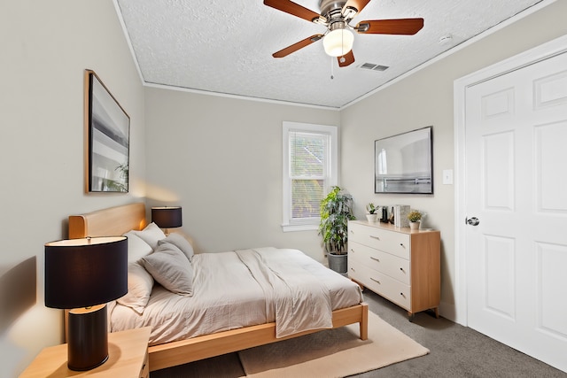 bedroom with ceiling fan, dark carpet, ornamental molding, and a textured ceiling