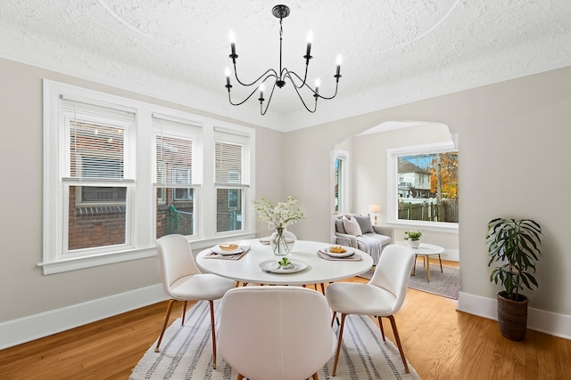 dining area featuring a notable chandelier, a textured ceiling, and hardwood / wood-style flooring