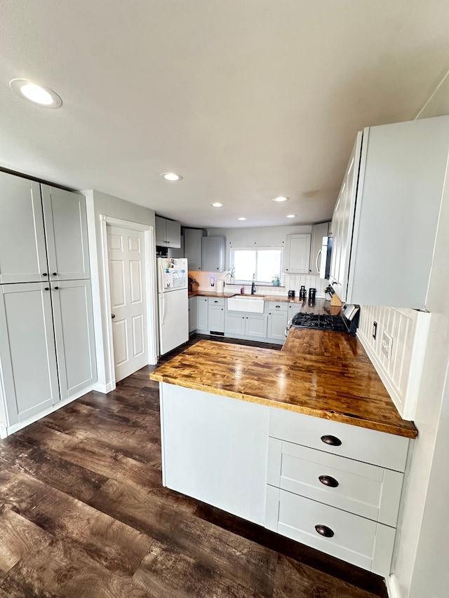 kitchen with sink, wood counters, dark hardwood / wood-style flooring, decorative backsplash, and appliances with stainless steel finishes