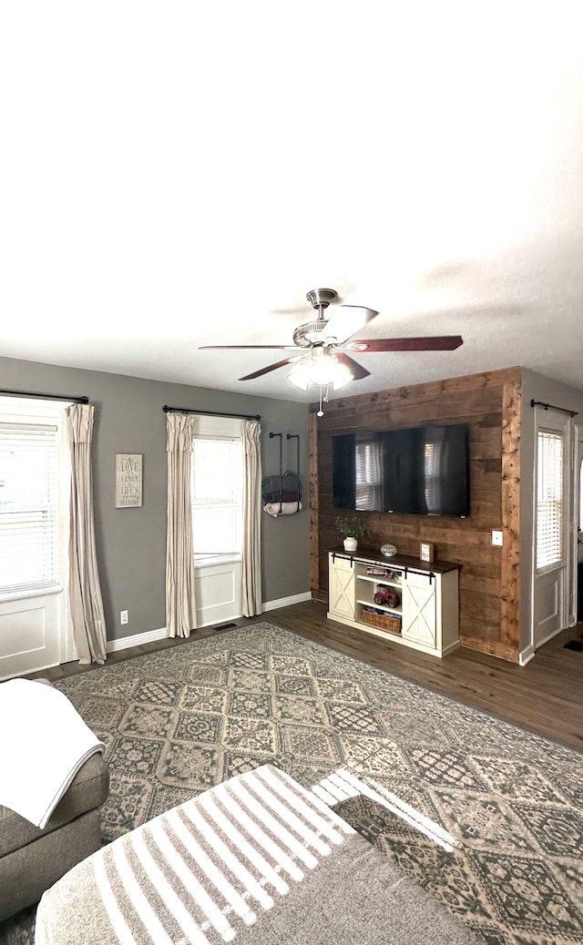 unfurnished living room featuring ceiling fan and dark hardwood / wood-style flooring