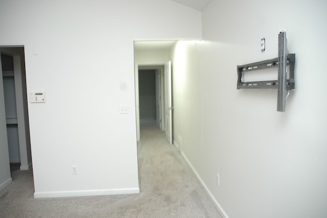 hall with light colored carpet and vaulted ceiling