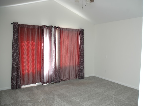 spare room featuring ceiling fan, carpet floors, and vaulted ceiling