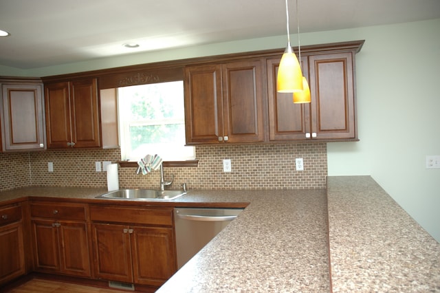 kitchen with backsplash, dishwasher, sink, and pendant lighting