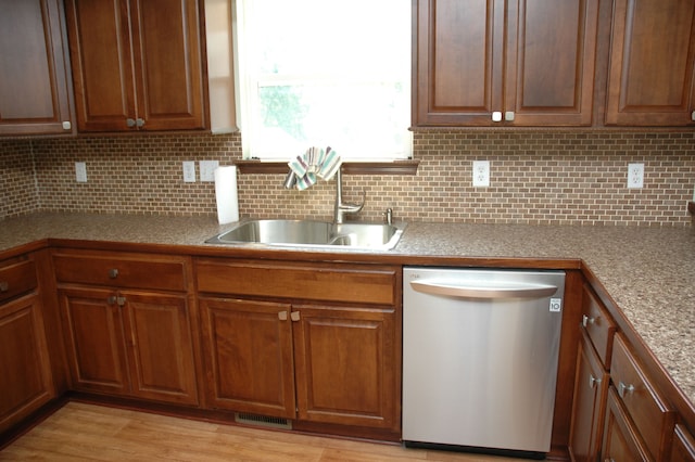 kitchen featuring tasteful backsplash, dishwasher, light hardwood / wood-style flooring, and sink