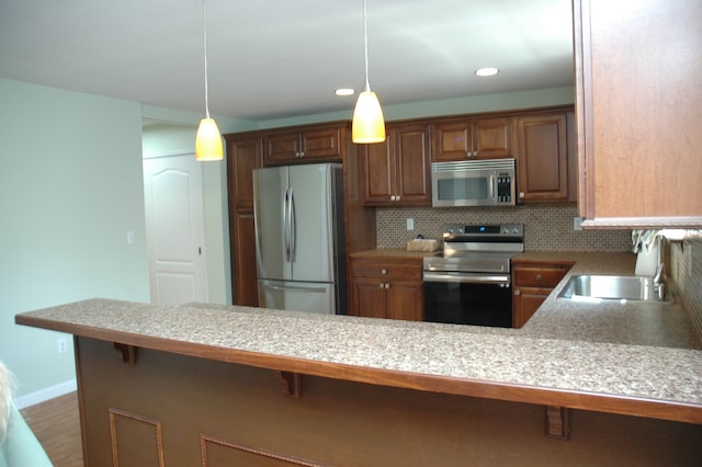 kitchen with stainless steel appliances, tasteful backsplash, kitchen peninsula, pendant lighting, and a breakfast bar area