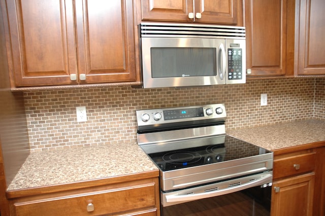 kitchen with backsplash, light stone counters, and stainless steel appliances