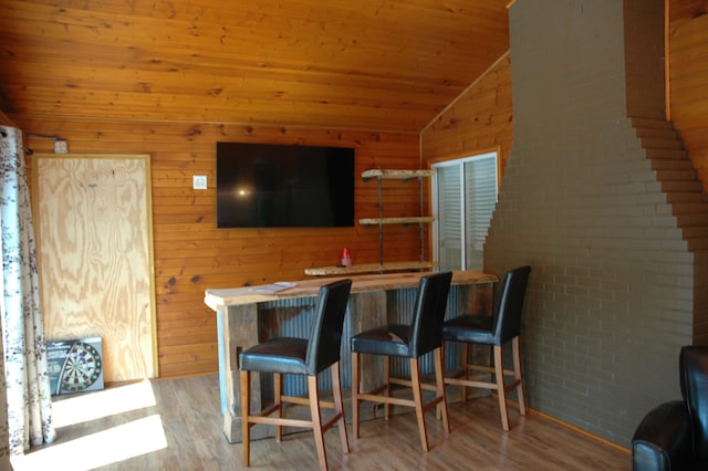 bar with wooden ceiling, wood walls, light hardwood / wood-style floors, and vaulted ceiling