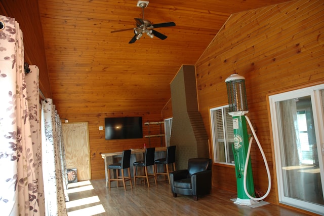 living room with wood ceiling, ceiling fan, wooden walls, wood-type flooring, and high vaulted ceiling