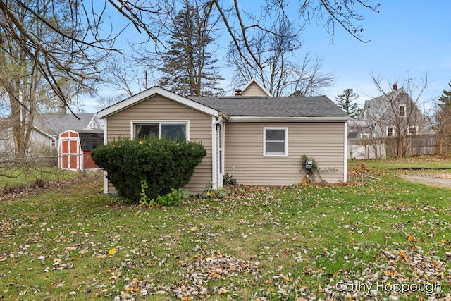 exterior space featuring a storage shed, a front lawn, an outdoor structure, and fence