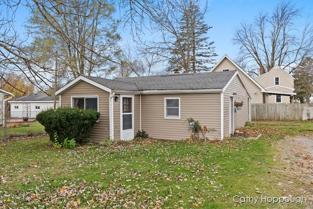 exterior space featuring roof with shingles, fence, and a front yard