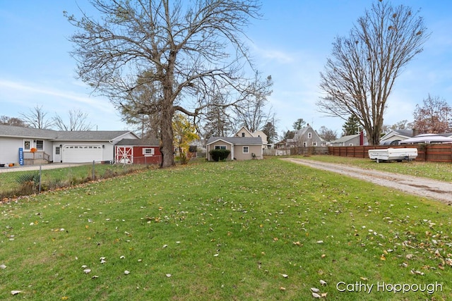 view of yard with a residential view, driveway, an attached garage, and fence