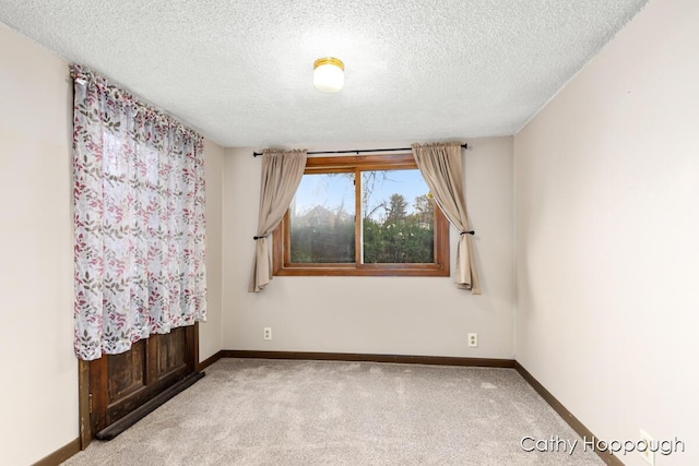 carpeted spare room with baseboards and a textured ceiling