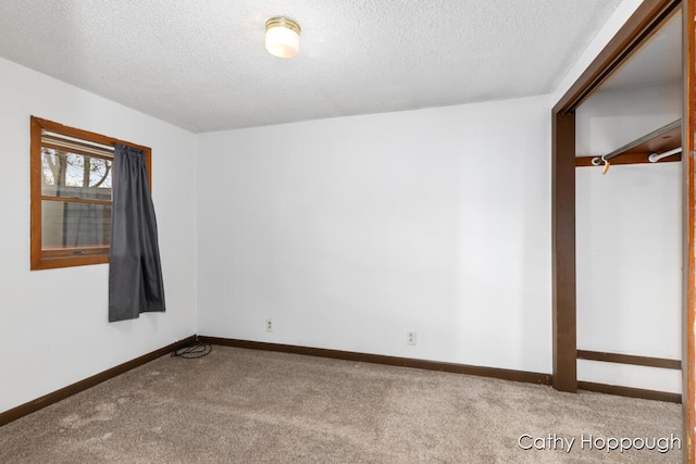 carpeted spare room featuring baseboards and a textured ceiling