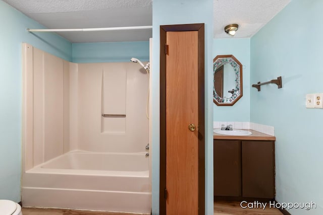 full bath with tub / shower combination, toilet, a textured ceiling, and vanity