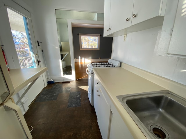 kitchen featuring white range with gas cooktop, sink, white cabinets, and dark wood-type flooring