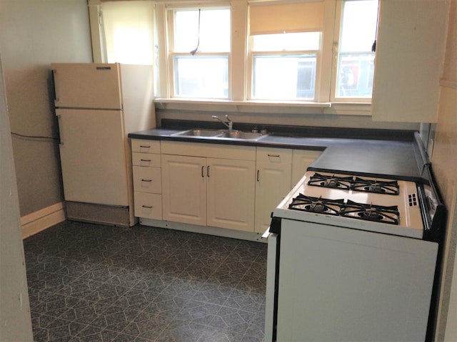 kitchen with white appliances, white cabinetry, a wealth of natural light, and sink