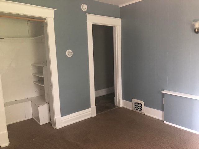 unfurnished bedroom with dark colored carpet and a closet