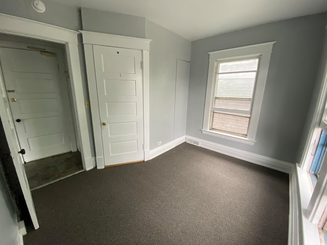 unfurnished bedroom with dark carpet