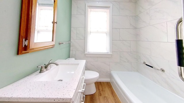 bathroom with a bathing tub, hardwood / wood-style floors, vanity, and toilet