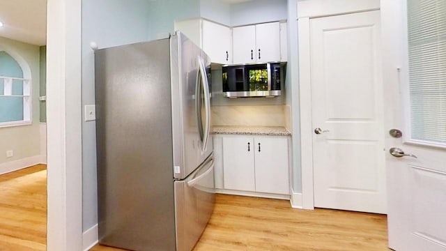 kitchen with appliances with stainless steel finishes, white cabinetry, and light wood-type flooring