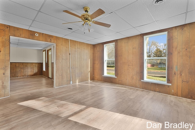 spare room featuring a paneled ceiling, ceiling fan, wood-type flooring, and wood walls