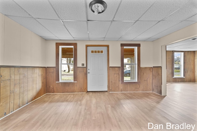 interior space featuring wood walls, light hardwood / wood-style flooring, and a drop ceiling