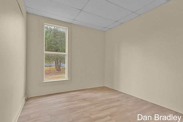 empty room with a drop ceiling and light wood-type flooring