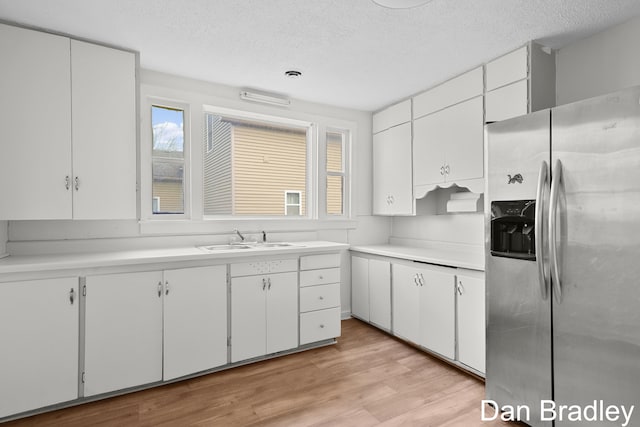 kitchen with white cabinets, sink, a textured ceiling, light hardwood / wood-style floors, and stainless steel fridge with ice dispenser