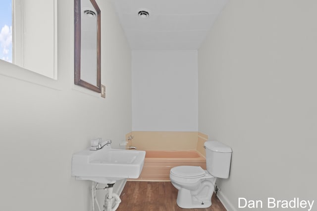 bathroom featuring wood-type flooring, toilet, a bathtub, and sink