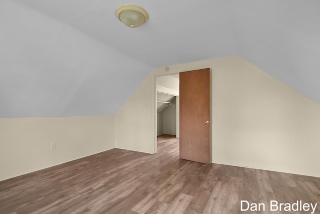 additional living space with light wood-type flooring and vaulted ceiling