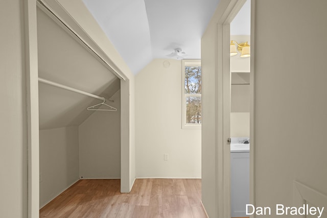 walk in closet featuring light hardwood / wood-style floors, lofted ceiling, and washer / dryer