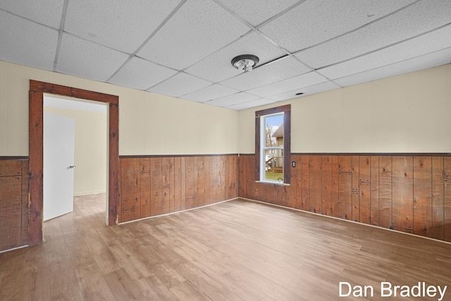 spare room with hardwood / wood-style floors, a paneled ceiling, and wooden walls