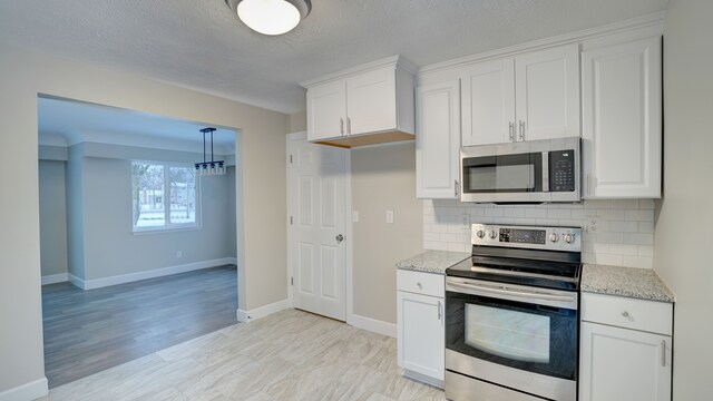 kitchen with stainless steel appliances, light stone counters, backsplash, a textured ceiling, and white cabinets