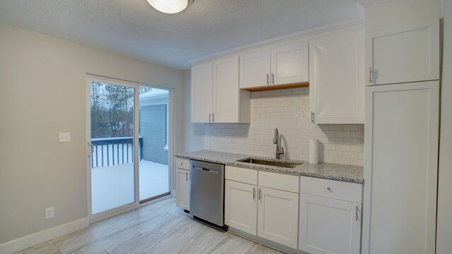 kitchen with backsplash, light stone counters, sink, dishwasher, and white cabinetry