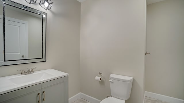 bathroom with toilet, vanity, and baseboards