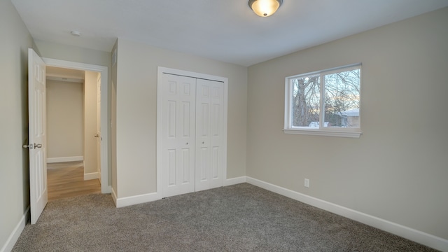 unfurnished bedroom with carpet floors, a closet, and baseboards