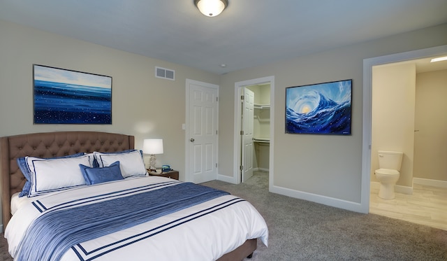 bedroom featuring baseboards, visible vents, ensuite bathroom, a walk in closet, and carpet flooring