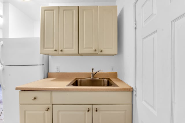 kitchen with cream cabinets, sink, and white fridge