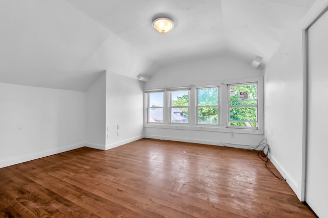 additional living space with hardwood / wood-style flooring and vaulted ceiling