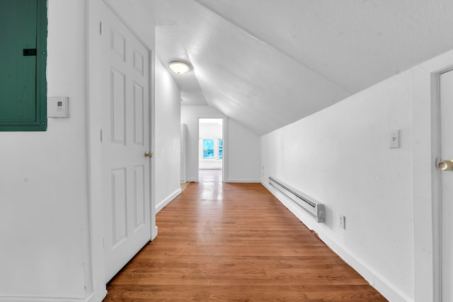 additional living space with electric panel, vaulted ceiling, a textured ceiling, a baseboard radiator, and light hardwood / wood-style floors