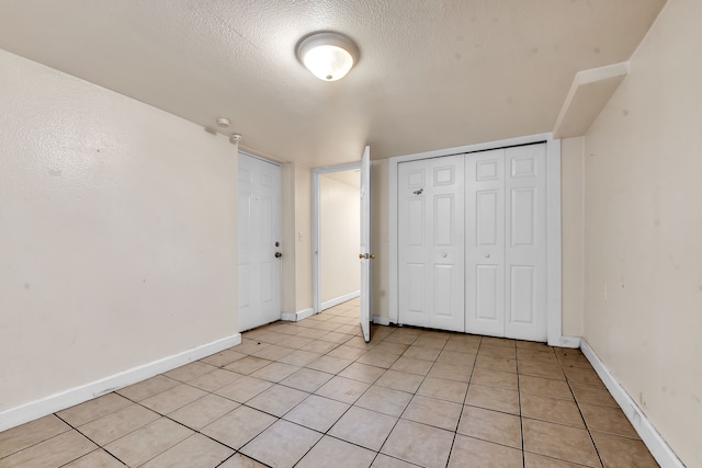 unfurnished bedroom with a textured ceiling, a closet, and light tile patterned flooring