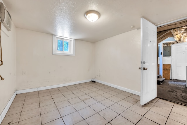 basement featuring light tile patterned floors, a textured ceiling, and a wall mounted AC