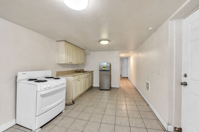 kitchen featuring stainless steel refrigerator, sink, light tile patterned floors, and white stove