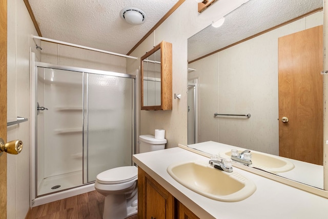 bathroom with a textured ceiling, crown molding, wood-type flooring, toilet, and a shower with shower door